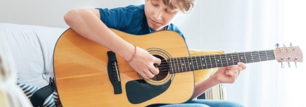 Teenage boy learning to play acoustic guitar