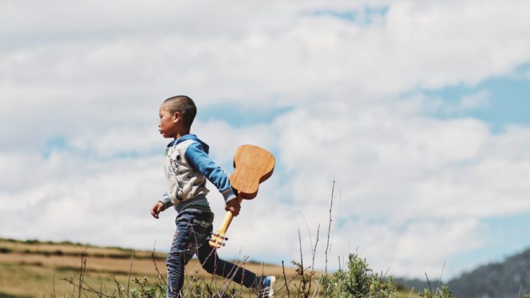 young boy walking and carrying ukulele