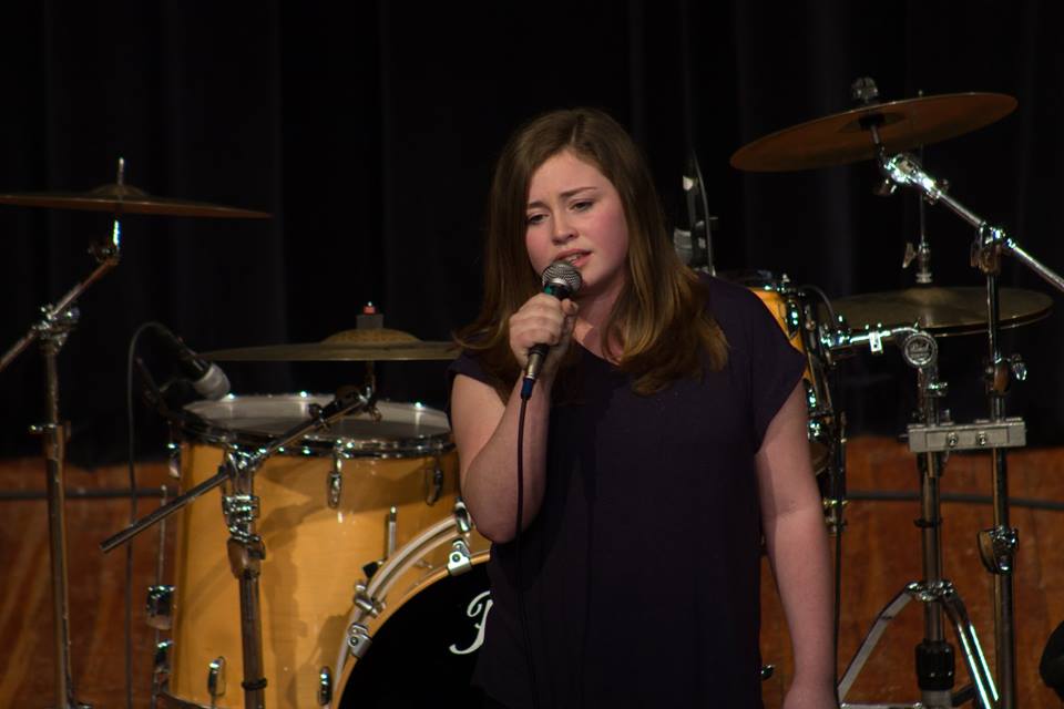 Young singer holding microphone on stage delivering a great performance
